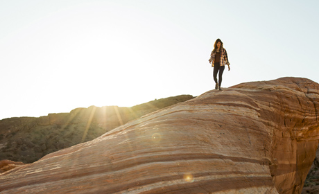 A person standing on a large rock in a scenic park