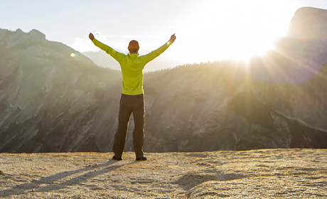 A person with both of their hands up looking into a scenic view