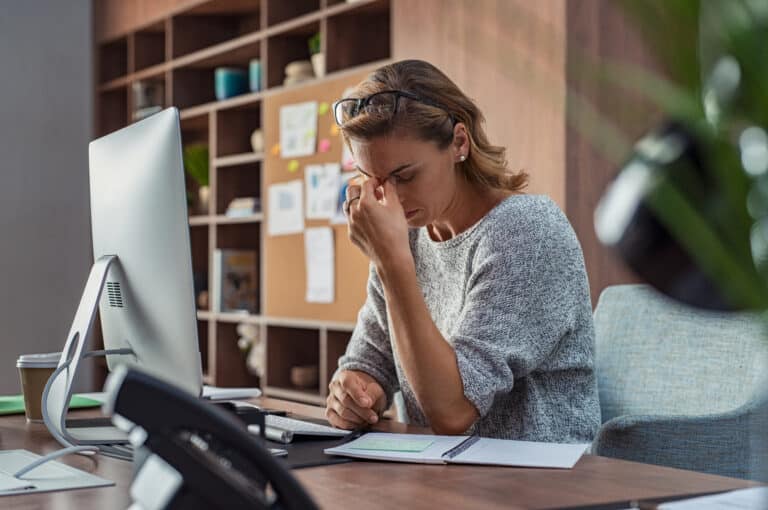 Woman at a computer with her head in her hand