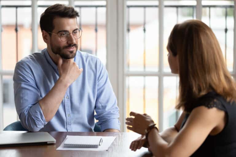 A man in glasses talking to a woman at work